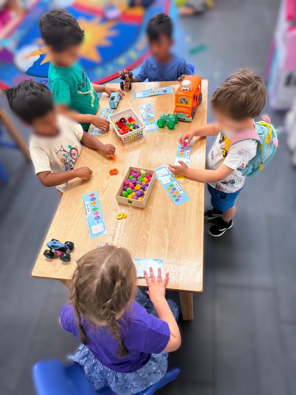 Children gathered around a wooden table exploring counting activities together